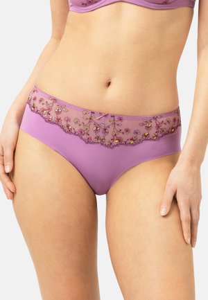 Donna che indossa biancheria intima in pizzo viola ricamata con motivi floreali e reggiseno abbinato, mostrata da metà addome fino alla parte superiore delle cosce.