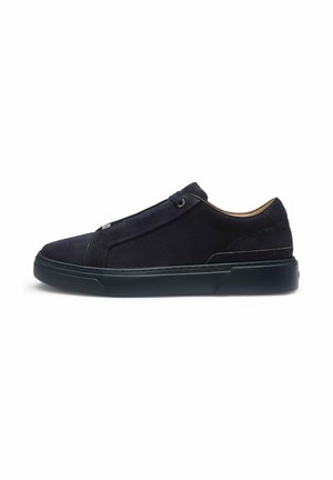 Sort ruskind lavtop sneaker med minimalistisk design, flad gummisål og ingen synlige snørebånd, vist i sideprofil på hvid baggrund.