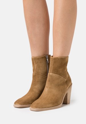 Braune Wildleder-Ankle Boots mit runder Spitze, seitlichem Reißverschluss und Blockabsatz. Glatte Textur, minimalistisches Design, geeignet für verschiedene Outfits.
