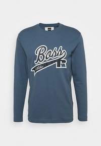 Sininen pitkähihainen T-paita, joka on valmistettu puuvillasta. Siinä on valkoinen "Boss" -logo ja "Athletic"-teksti erottuvilla väreillä. Klassinen pyöreä pääntiema.