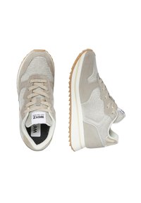 Sneakers grigi chiari e beige con pannelli in rete e suede, chiusura con lacci e suole in gomma naturale, mostrati da viste superiori e laterali.