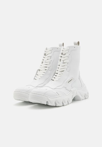 White high-top boots made of smooth leather, featuring a chunky sole, front lacing, and a pull tab on the heel. Subtle logo detail visible.