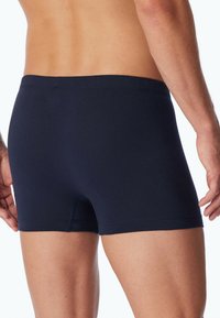 Marinblå bomullsboxershorts med en åtsittande passform, med en mjuk elastisk midja och slät yta, utan synliga mönster eller detaljer.