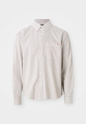 Camisa blanca de manga larga con botones, con finas rayas verticales rojas y un bolsillo en el pecho que presenta un pequeño logo rojo y azul.