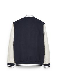 Marinblå skolvärjarjacka med vita läderärmar och randig ribbad krage, manschetter och nederdel, visad bakifrån på en vit bakgrund.