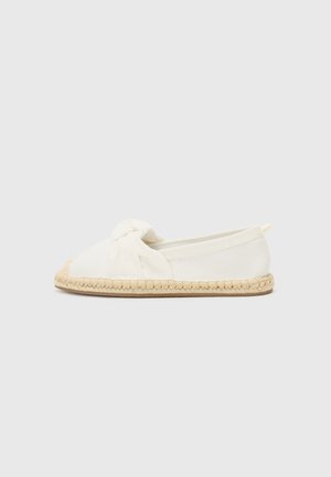 Scarpa slip-on in tela bianca con dettaglio anteriore annodato, suola in corda di juta e design minimalista. Forma piatta con punta arrotondata.