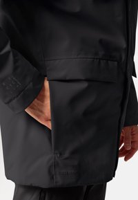 Zwarte waterdichte jas met een soepele textuur, voorzien van een zijzak en een reliëf "CEPLEX ACTIVE" merknaam nabij de onderrand.