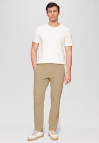 Beige chino's en een witte crew neck t-shirt, gecombineerd met beige en witte sneakers. Glad materiaal, slim fit en een minimalistisch ontwerp.