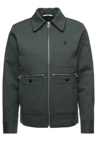 Grüne Jacke aus strukturiertem Stoff mit spitzem Kragen, Frontreißverschluss und mehreren Reißverschluss- und Knopftaschen.