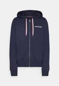 Felpa zip nera con cappuccio di colore blu navy, dotata di tasca frontale, testo del logo bianco, coulisse a contrasto e polsini e orlo a coste. Texture del tessuto morbida.