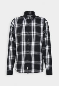 Svart och vit rutigt skjorta med knappar och klassisk krage, med ett rutmönster och svarta knappar mot en bomullstyngd.