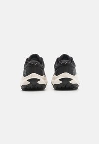 Sapatilhas desportivas pretas com um upper texturizado, entressola branca e sola exterior em borracha preta. Apresenta uma marca no calcanhar e detalhes refletivos.