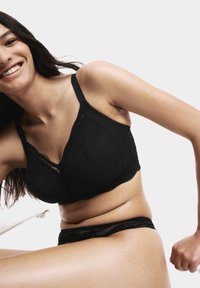 Black bra with textured fabric and lace detailing, featuring wide straps and a triangle shape. Pairing with a matching black lace brief.