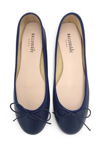 Bailarinas de color azul marino con un exterior de piel lisa, punta redonda y un pequeño lazo en la parte delantera. Plantilla beige con el nombre de la marca.