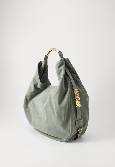Vihreä mokkakangasta oleva hobo-laukku, jossa on kaareva kultametallinen kahva ja kohotettu "Moschino"-logo sivussa, pehmeästä ja teksturoidusta kankaasta.