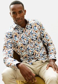 Mehrfarbiges Hemd mit abstraktem Muster in Blau, Braun und Weiß, mit klassischem Kragen und langen Ärmeln.