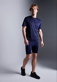 T-shirt atlético azul-marinho e calções combinando, feitos de um tecido elástico. Ténis completam o visual, oferecendo um design simples e elegante.