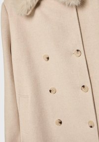 Beige wollen jas met een bontkraag, dubbele knopen, gestructureerde stof, zes ronde knopen en een zijzakdetail.