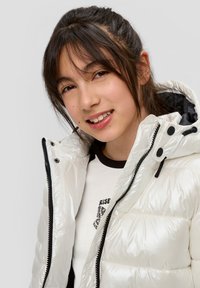 Weißer Puffer-Jacke mit glänzender Oberfläche, Reißverschluss und schwarzen Akzenten. Das Innere hat ein kontrastierendes dunkles Futter. Auffällige Kapuze mit Bungee-Kordel.