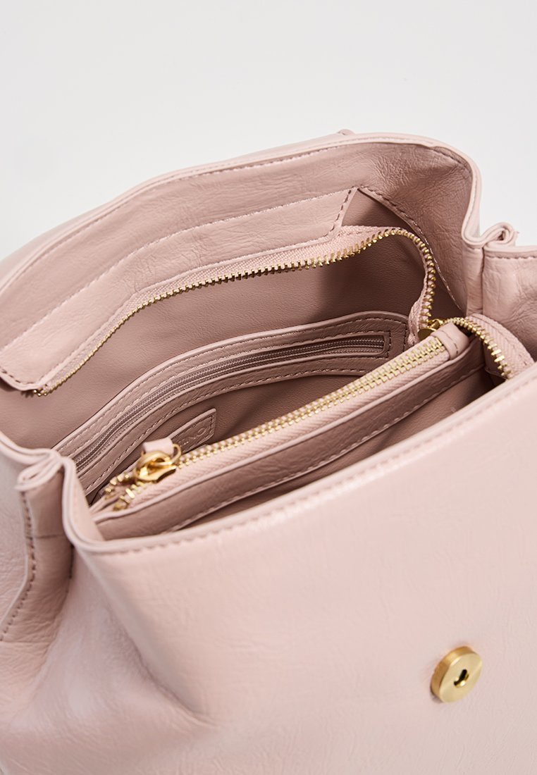 Rosa Kunstleder-Handtasche mit goldenen Reißverschlüssen und Beschlägen. Verfügt über mehrere Fächer und einen magnetischen Druckverschluss. Glatte Textur.