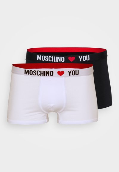 Two pairs of boxer shorts featuring a white pair with red and black elastic waistband and a black pair with a matching waistband.
