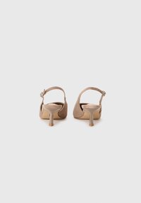 Sandali con tacco alto in suede beige, con cinturino posteriore, caratterizzati da un piccolo tacco a blocco e una fibbia decorativa sul cinturino alla caviglia.