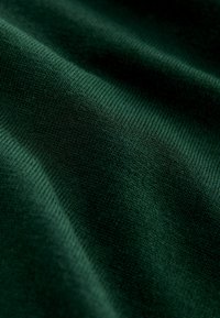 Material tricotat de culoare verde închis, cu o textură moale, având un model fin vizibil și o structură de tricot ridicată, evidențiind pliurile și catrințele.