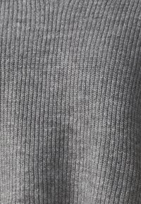 Pull en tricot gris avec une texture côtelée, présentant des nuances de gris variées pour profondeur et détail. Matériau doux de moyenne épaisseur.