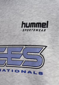 Szara bluza z logo "hummel SPORTSWEAR" w kolorze czarnym. Z napisem "NATIONALS" w kolorze niebieskim, ozdobionym pasiastymi niebiesko-białymi literami.