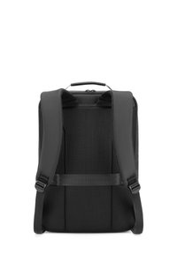 Mochila negra con correas de malla acolchadas y un asa plana en la parte superior. La parte trasera tiene un diseño texturizado con hebillas laterales ajustables.