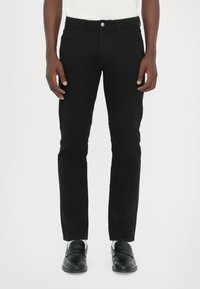 Jeans negri din denim cu croială dreaptă, cinci buzunare, închidere cu nasture argintiu și o textură netedă. Purtați cu mocasini negri.