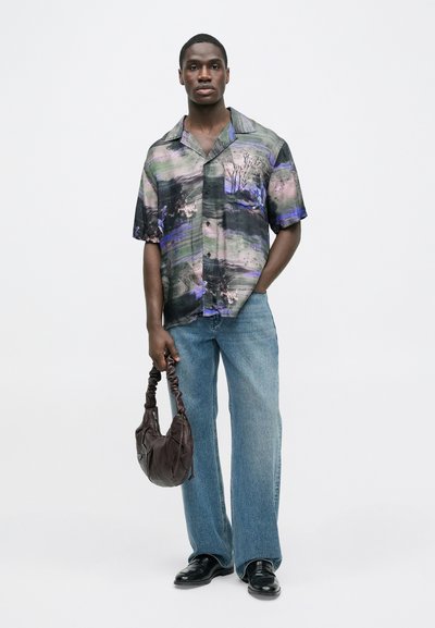 Πουκάμισο με κοντά μανίκια και κουμπιά, με αφηρημένο πολύχρωμο μοτίβο, συνδυασμένο με φαρδιά τζιν παντελόνια ανοιχτό μπλε και καφέ χαλαρή τσάντα.
