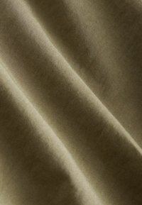 Olivgrüner Stoff mit einer glatten, matten Oberfläche; mit subtilen diagonalen Linien und Falten, die auf ein leichtes, atmungsaktives Material hindeuten.