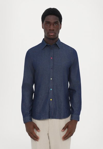 Chemise en denim à boutons, bleu foncé avec des boutons colorés (violet, rose, bleu, jaune), manches longues, col et ourlet légèrement arrondi.