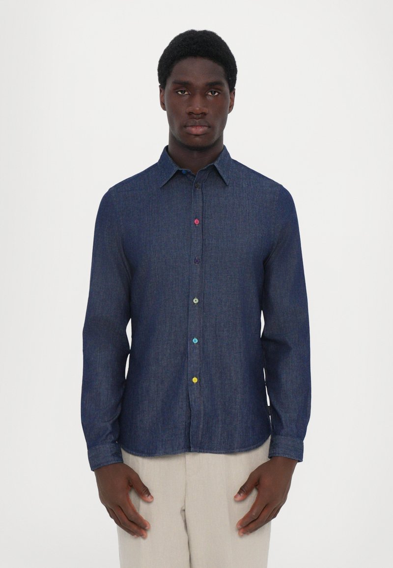 Denim button-up shirt, dark blue with colorful buttons (purple, pink, blue, yellow), long sleeves, collar, and slightly curved hem.