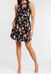 Musta kangas kukkamekko, jossa on olkaimeton muotoilu, avainaukko kaula-aukko, taskut ja levenevä hame vaaleanpunaisilla ja valkoisilla kukkakuoseilla.