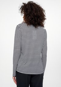 Czarna i biała, paskowana koszula z długim rękawem o luźnym kroju. Miękka tkanina z okrągłym dekoltem, widoczne szwy wzdłuż ramion.