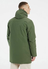 Parka imperméable verte avec capuche, manches longues et coupe droite. Présente un branding subtil au dos et une texture lisse.