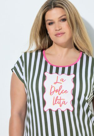 Donna con capelli biondi lunghi che indossa una camicia verde e bianca a righe verticali con bordi rosa e la scritta "La Dolce Vita" sul davanti.