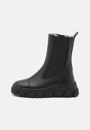 Bottine en cuir noir avec semelle à crampons épaisses, panneau latéral élastique, languette à l’arrière et doublure intérieure beige douce.