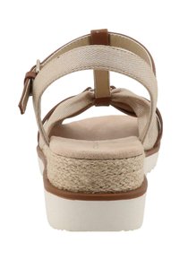 Beige sandaalit, joissa on kudottu rakenne, säädettävä ruskea hihna, pehmustettu pohja ja valkoinen alusta, jossa on juutista valmistettua detaljityötä.