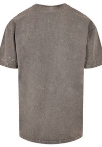 Graues Oversized-T-Shirt aus Baumwolle mit kurzen Ärmeln, rundem Ausschnitt und einer strukturierten Oberfläche mit dezenten Abnutzungsspuren.