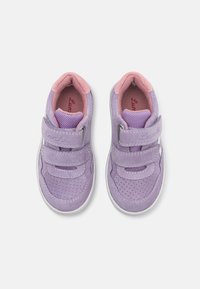 Lilla semskede sneakers med rosa accenter, med doble Velcro-stropper og perforert design for pusteevne, på en hvit gummisåle.
