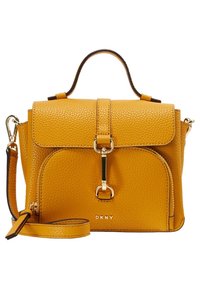 Żółta torebka ze skóry z fakturą ziarenek, o usztywnionym kształcie, z górnym uchwytem i odpinanym paskiem na ramię. Posiada przednią klapę i złote detale.