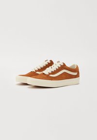 Brown suede sneakers with white laces and side stripes, featuring a low-top design and a textured finish. Cream rubber soles.