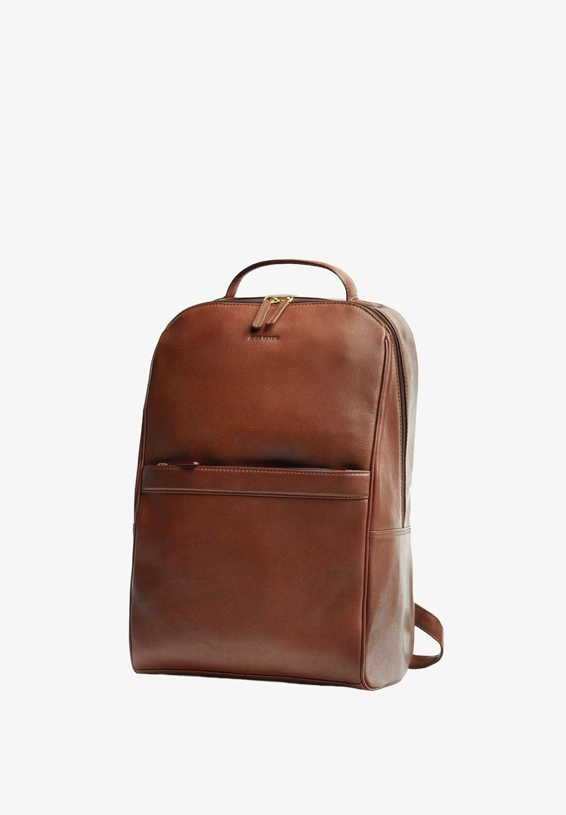 Ruskea nahkainen reppu, jossa on tyylikäs muotoilu. Siinä on etutasku, kantokahva ja säädettävät olkahihnat. Kultaiset metalliosat.