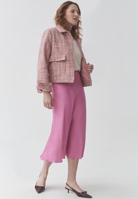 Roosa tweed jakk kraega, koos pika roosa seelikuga. Terava nina ja avatud kontsaga tume lilla kingad. Lihtne pluus all.