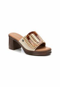 Sandalo scivoloso beige con accento intrecciato in oro e marrone, dettaglio della fibbia trasparente e tacco in legno massiccio. Soletta morbida e testurizzata.