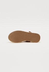 Brown rubber sandal sole with a textured pattern, featuring a flat design and slight arch, suitable for casual wear.