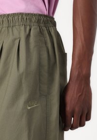 Khaki Nike shorts med elastisk talje, en sidelomme og broderet logodetalje. Letvægtsstof med en glat tekstur.